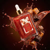 Bottle of Glampton Body Oil caramel  rouge surrounded by chocolate pieces and splashes on a dark background