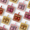 Glampton 2-piece gift sets arranged in a repeating pattern, featuring Shimmer Fragrance Mist and Shimmering Body Oil duos in Sweet Sugar, Crushed Cherry, Caramel Rouge, and Vanilla Sun Musk.