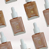 Glampton Illuminating Drops and Endless Summer Glow bronzing drops shown in a repeated pattern on a light background.